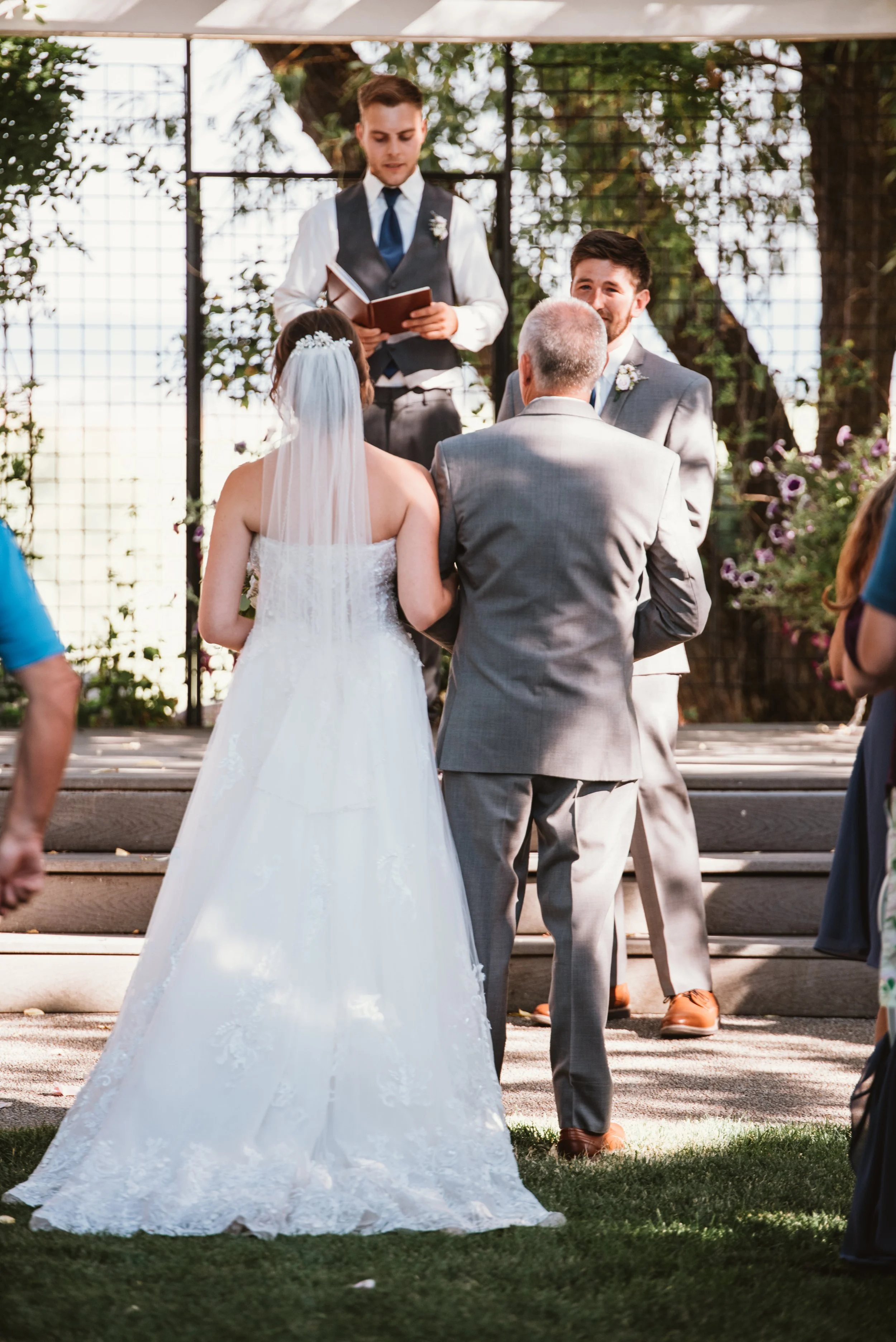 Bride and groom at outdoor wedding ceremony with officiant.