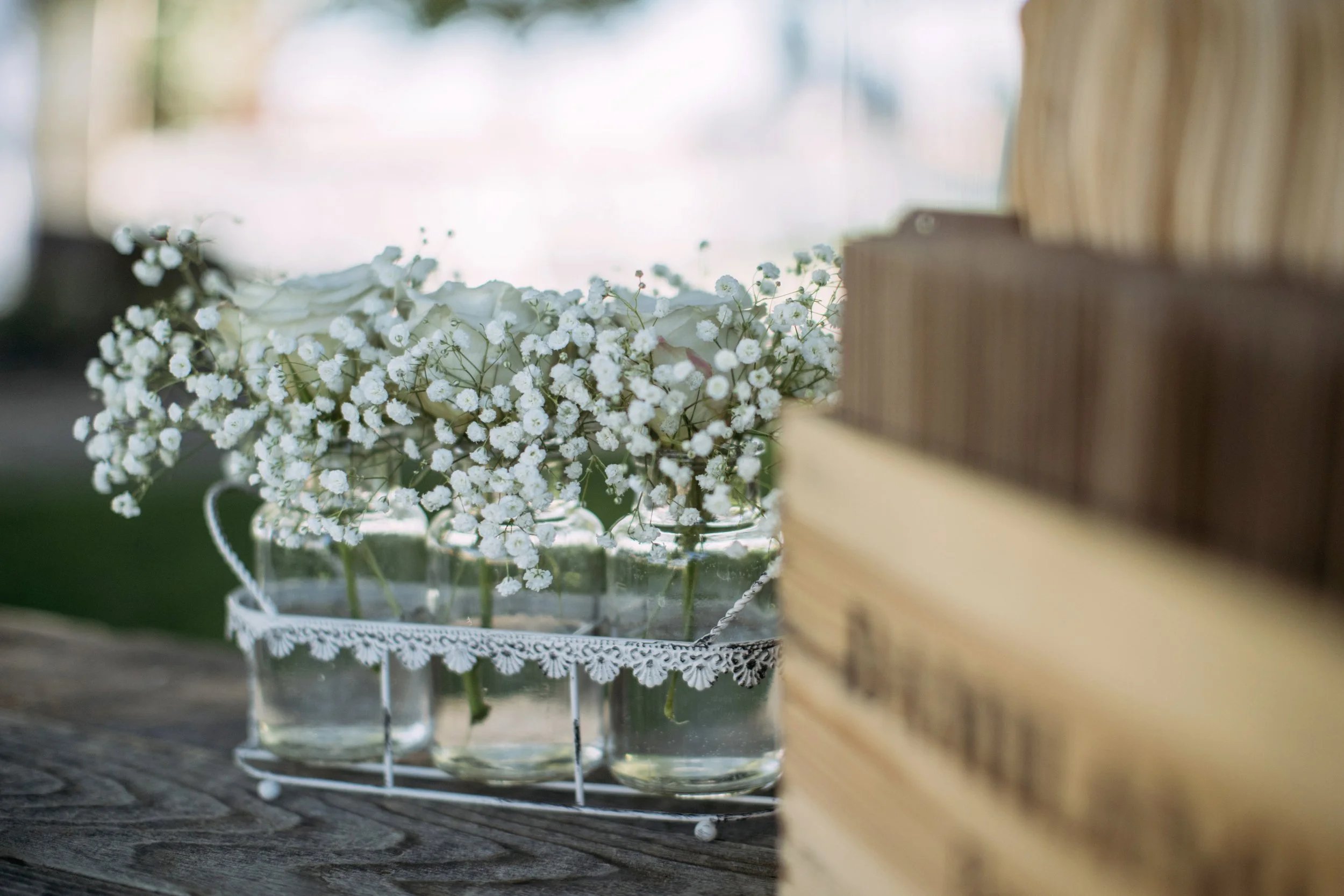 Small white flowers in glass jars on a wooden table