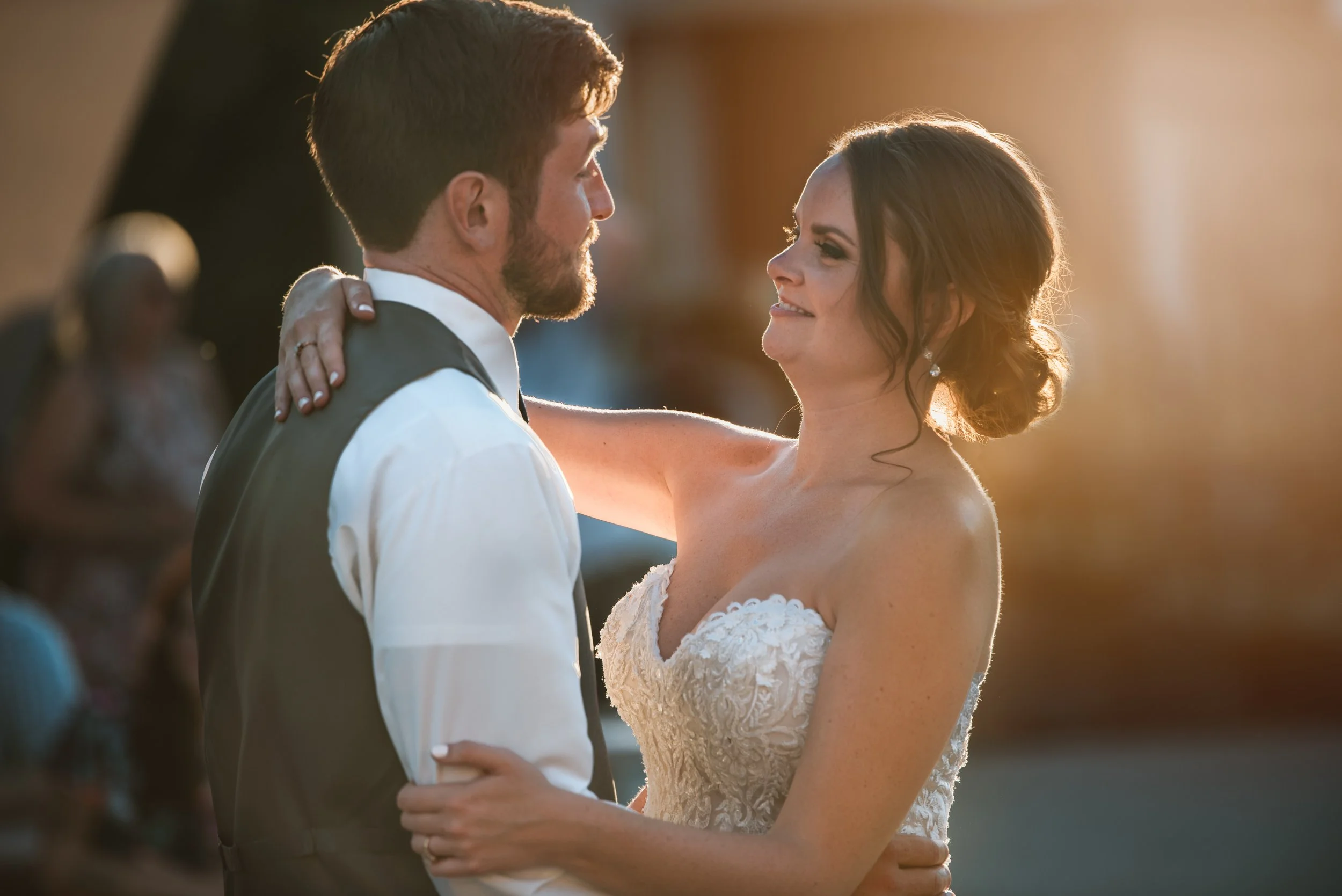 Bride and groom dancing at a wedding with warm sunset lighting.