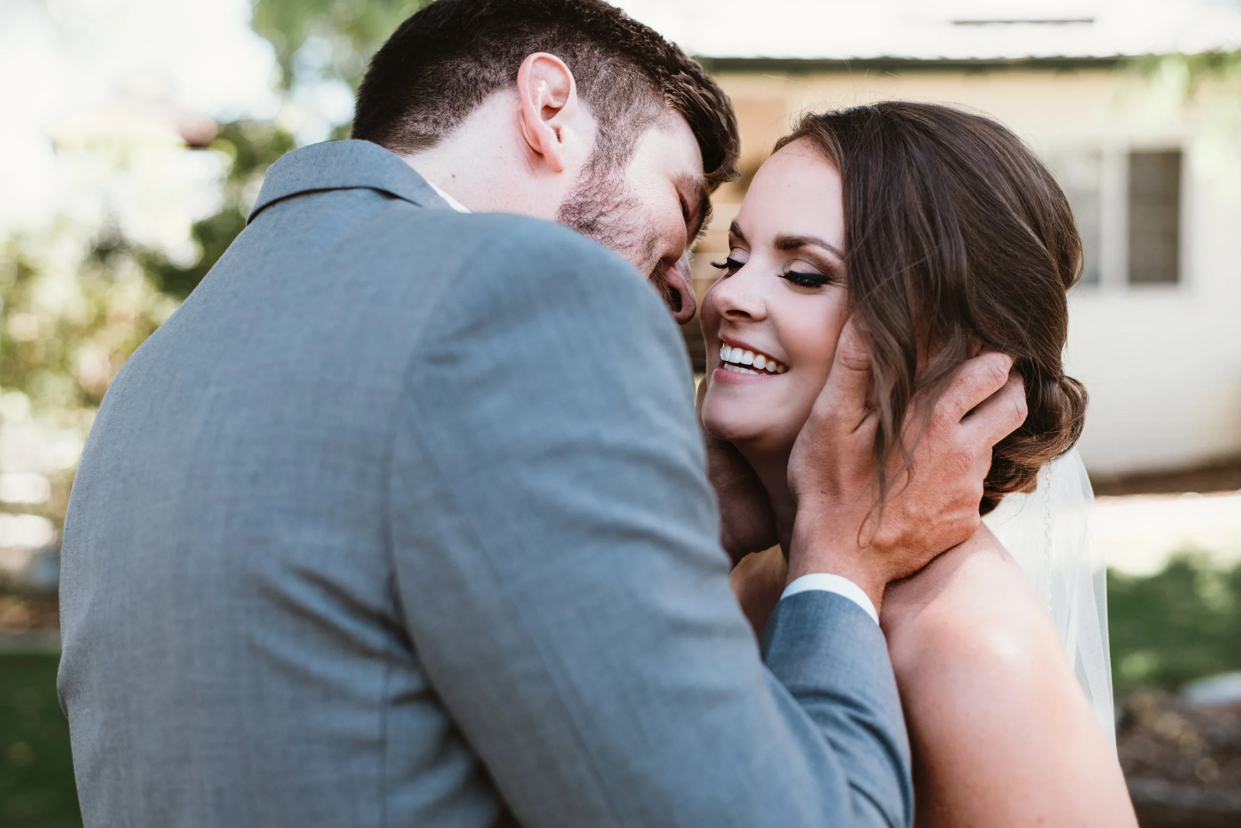 Smiling couple embracing, man in suit and woman in bridal dress.