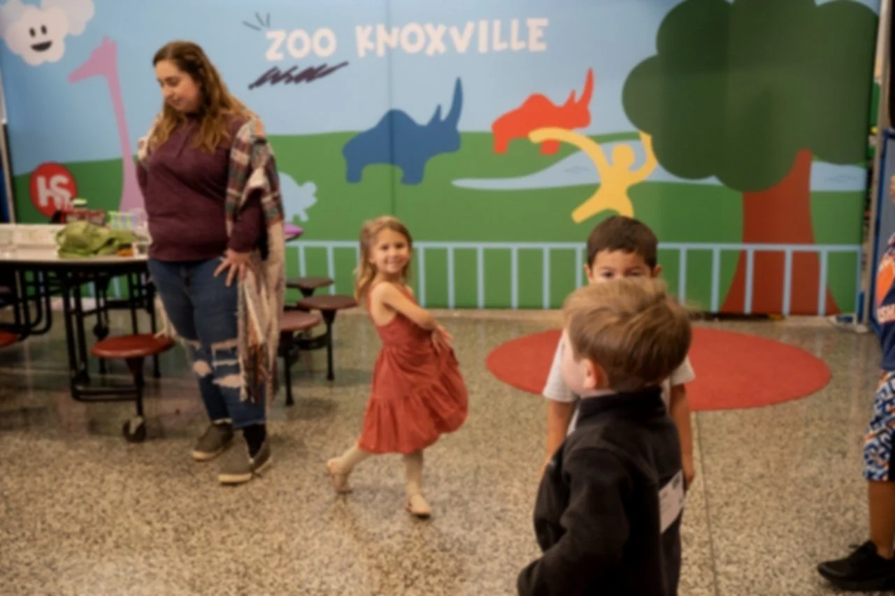 Children and a woman in a room with "Zoo Knoxville" mural.