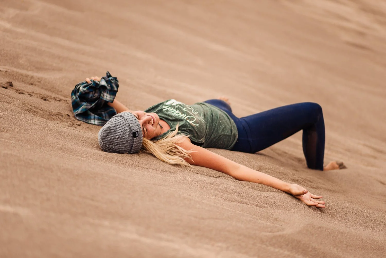 Adventure lifestyle product photography of a blonde girl laying in the sand at Great Sand Dunes National Park in Colorado for Akinz Boardwear