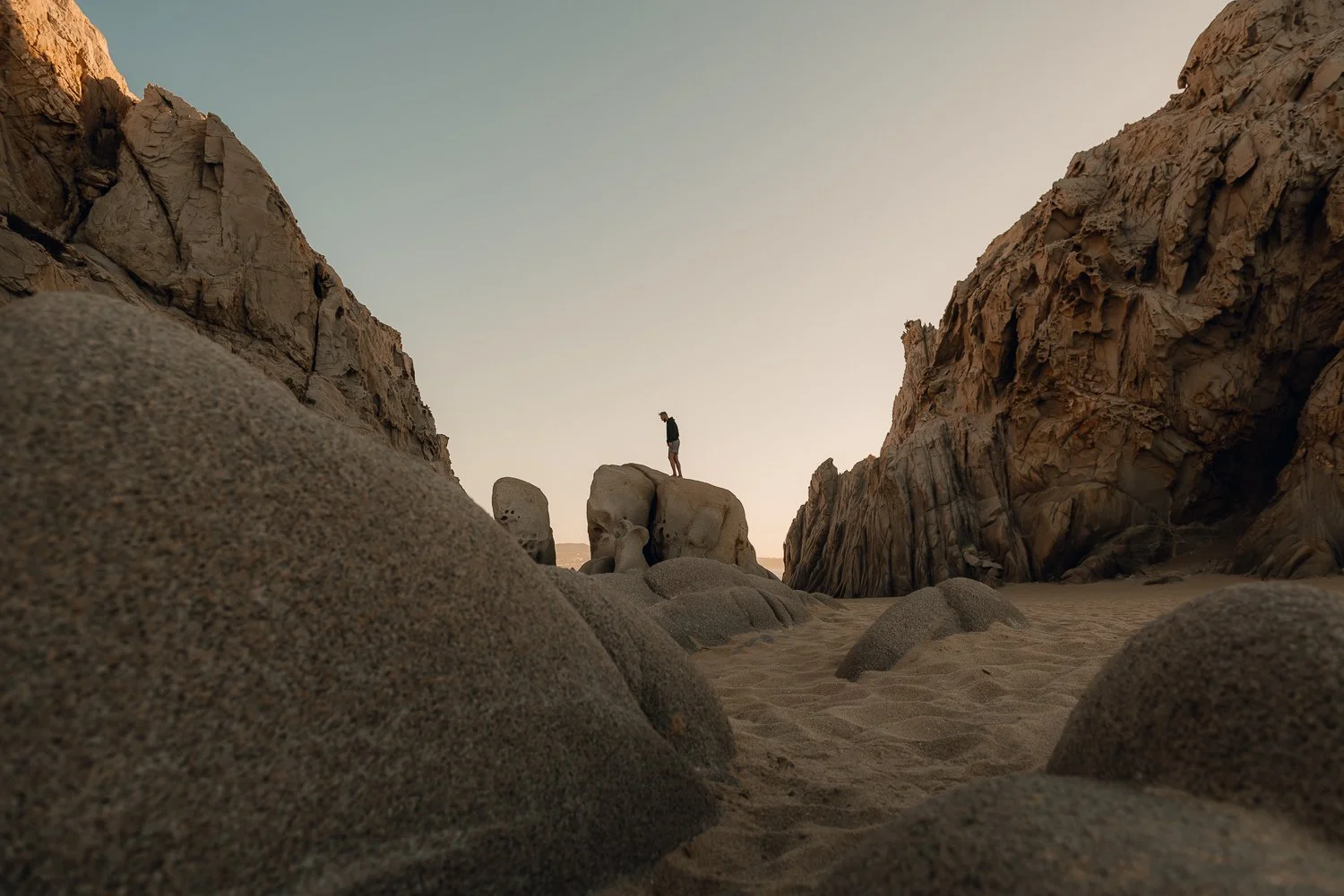Adventure travel photography of a man climbing a rock formation on lover's beach in Cabo San Lucas, Mexico