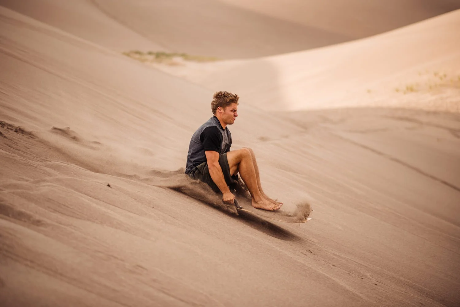 Adventure lifestyle product photography of a guy sandboarding in Great Sand Dunes National Park in Colorado for Akinz Boardwear