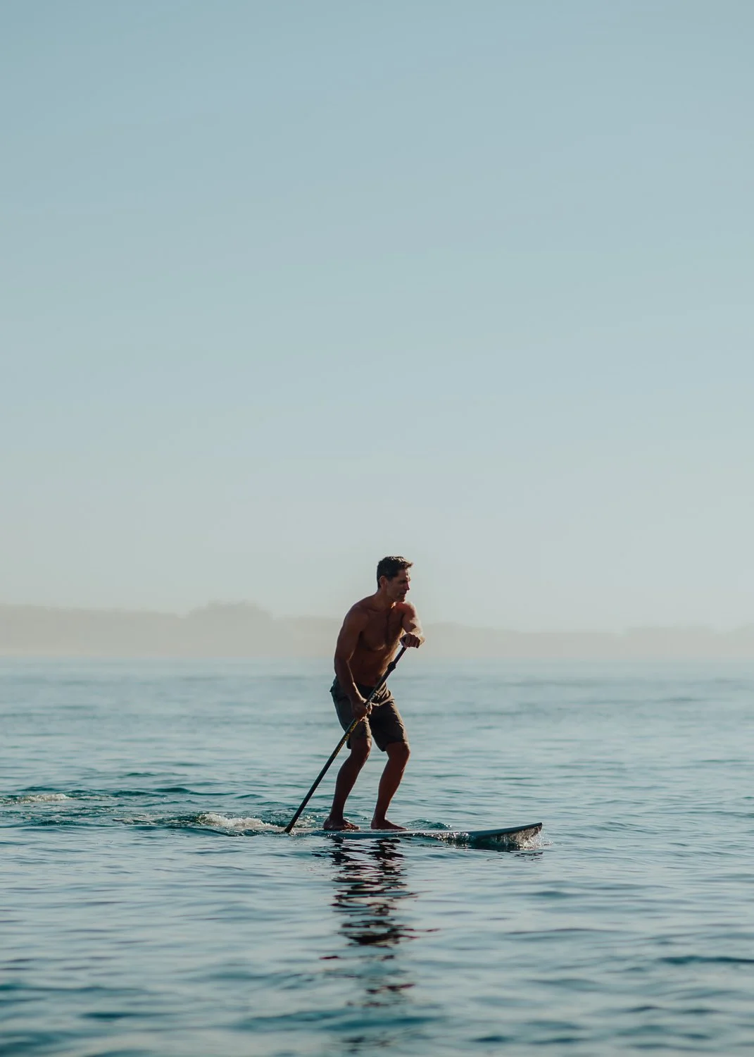 Adventure lifestyle photography of male stand up paddle boarding to Lover's Beach in Cabo San Lucas, Mexico