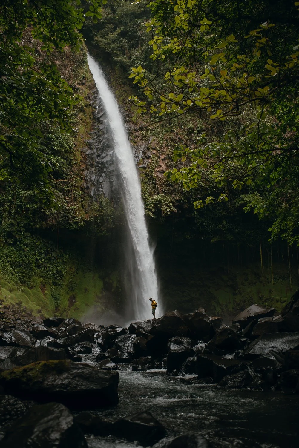 Landscape photograph of a backpacker standing at the base of La Fortuna Waterfall in Costa Rica
