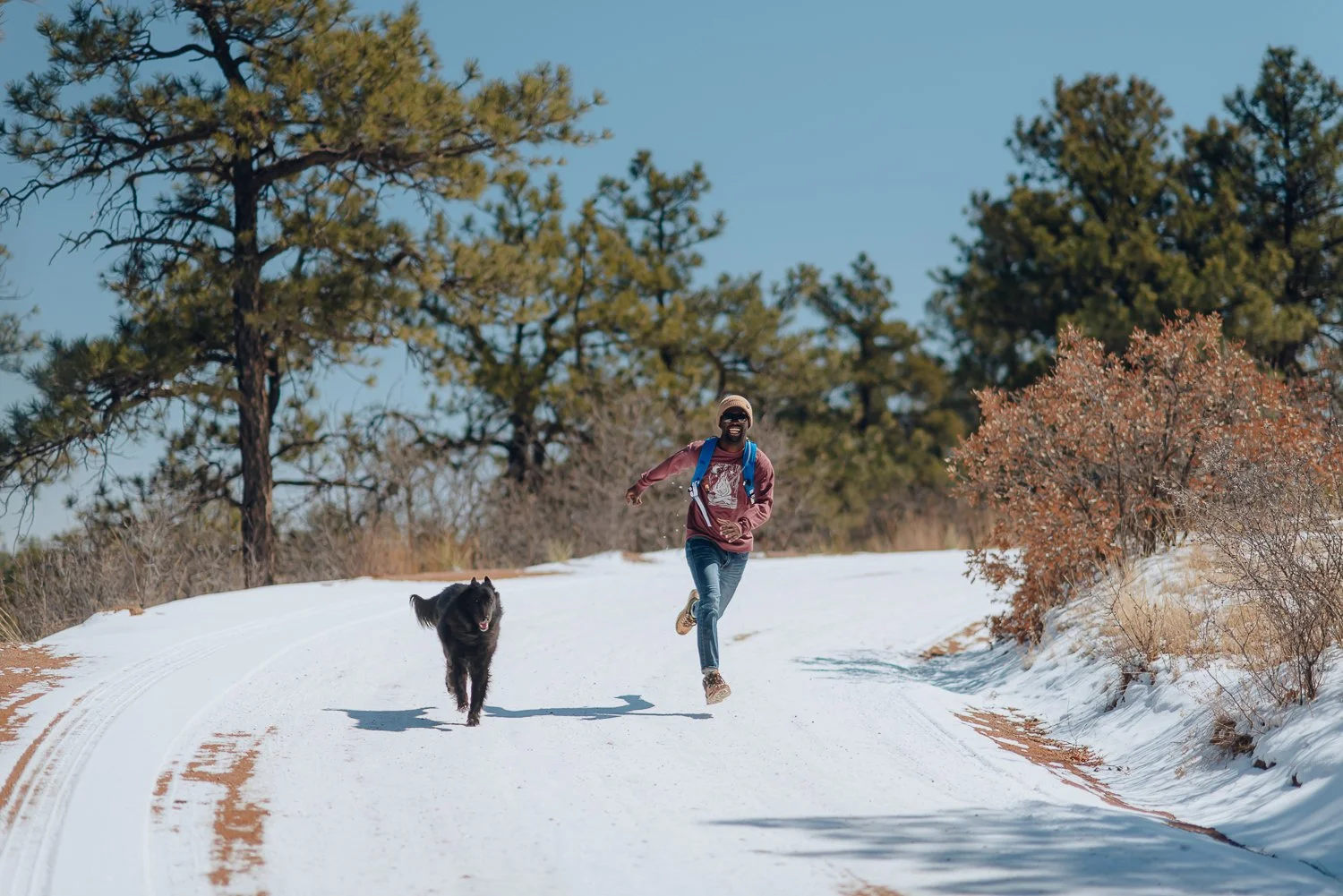 Professional lifestyle photography of young male model wearing a tan Akinz Boardwear beanie and red long sleeve tshirt in the snowy mountains in Colorado Springs, Colorado