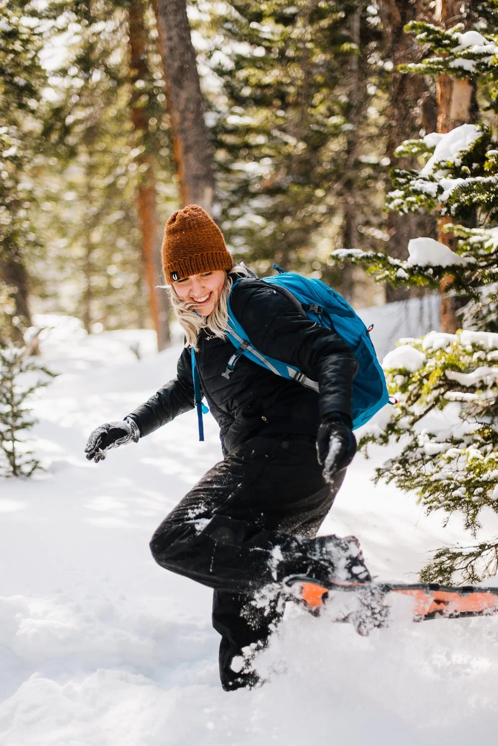 Lifestyle brand photography of blonde girl playing in the snow in the woods while snowshoeing