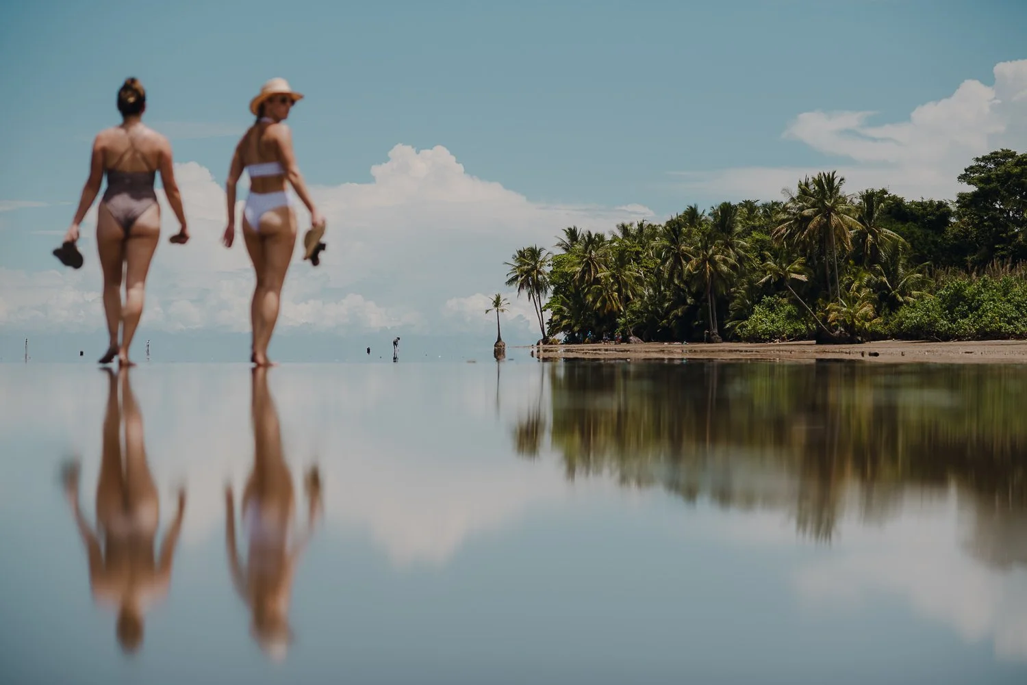 Travel photography of reflections of girls walking on Whale Tail beach in Uvita, Costa Rica