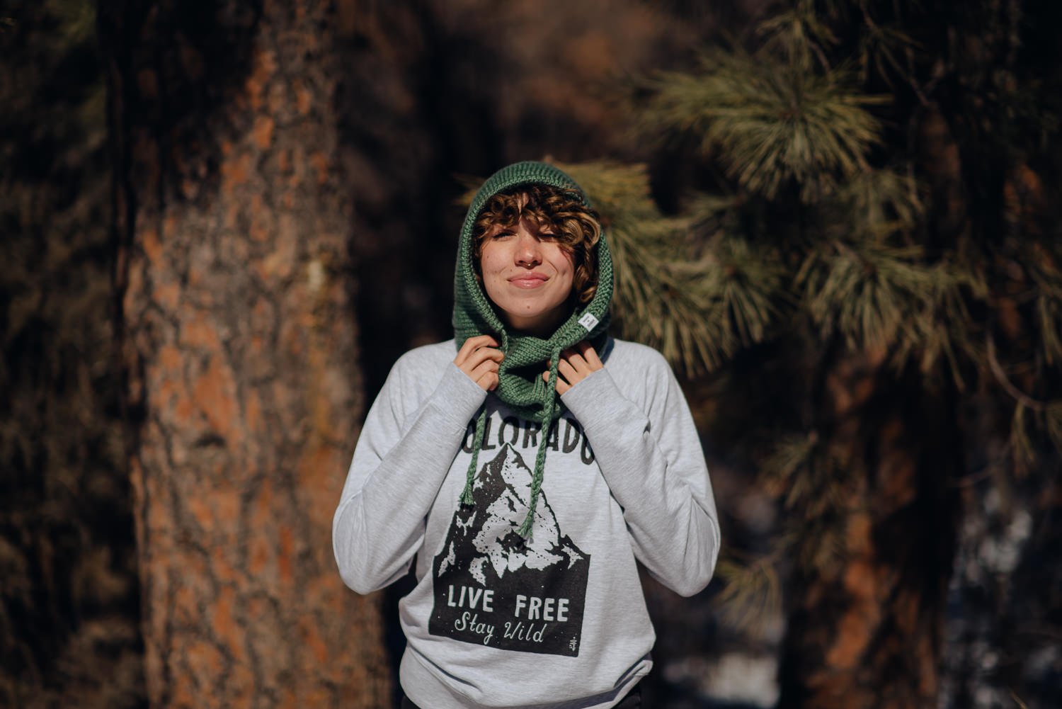 Professional lifestyle photography of young Puerto Rican model with short, curly, brown hair wearing Akinz Boardwear clothing in the snowy mountains in Colorado Springs, Colorado