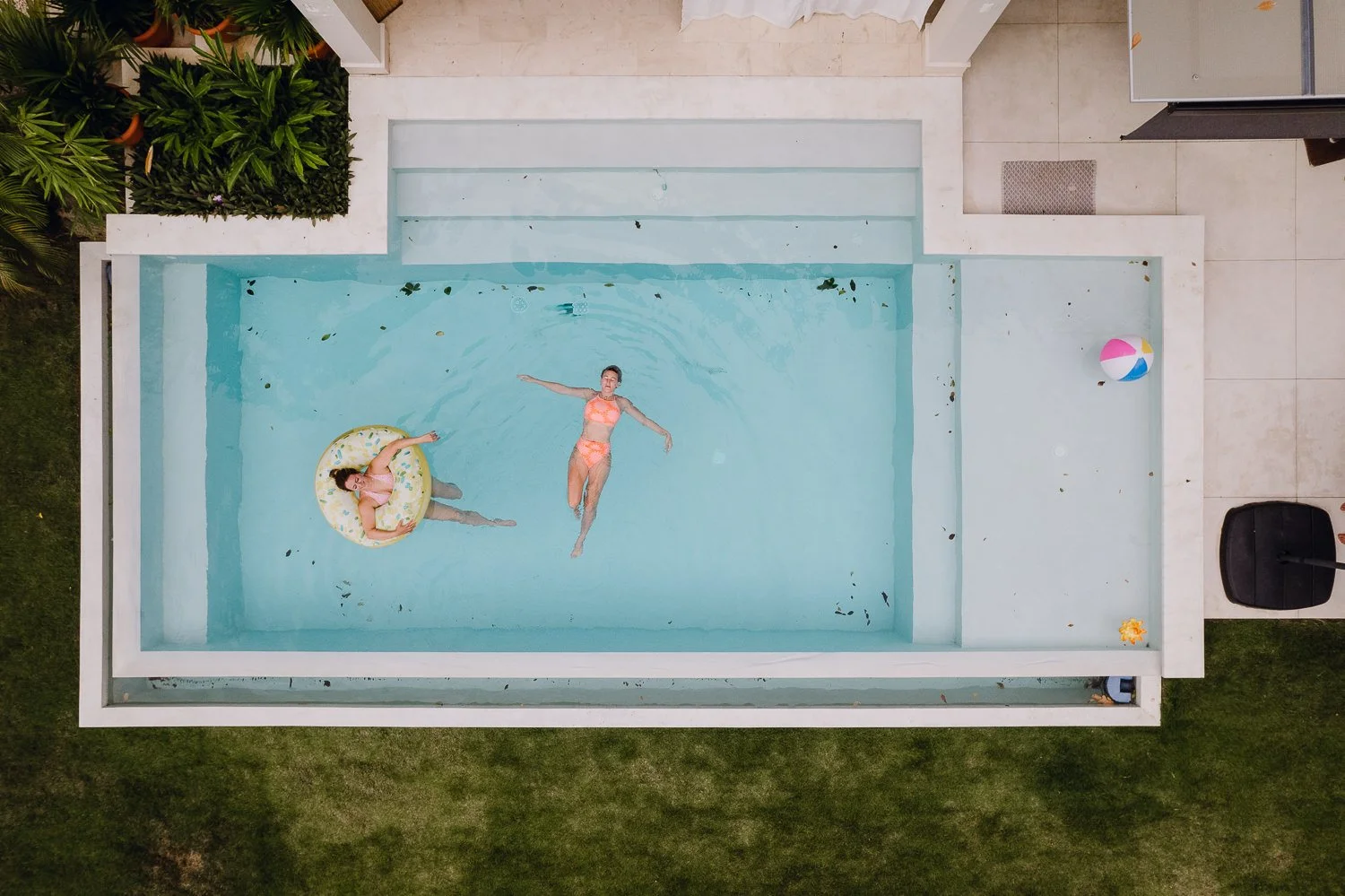 Travel drone photograph of two girls relaxing in a modern pool in a unique airbnb in Costa Rica