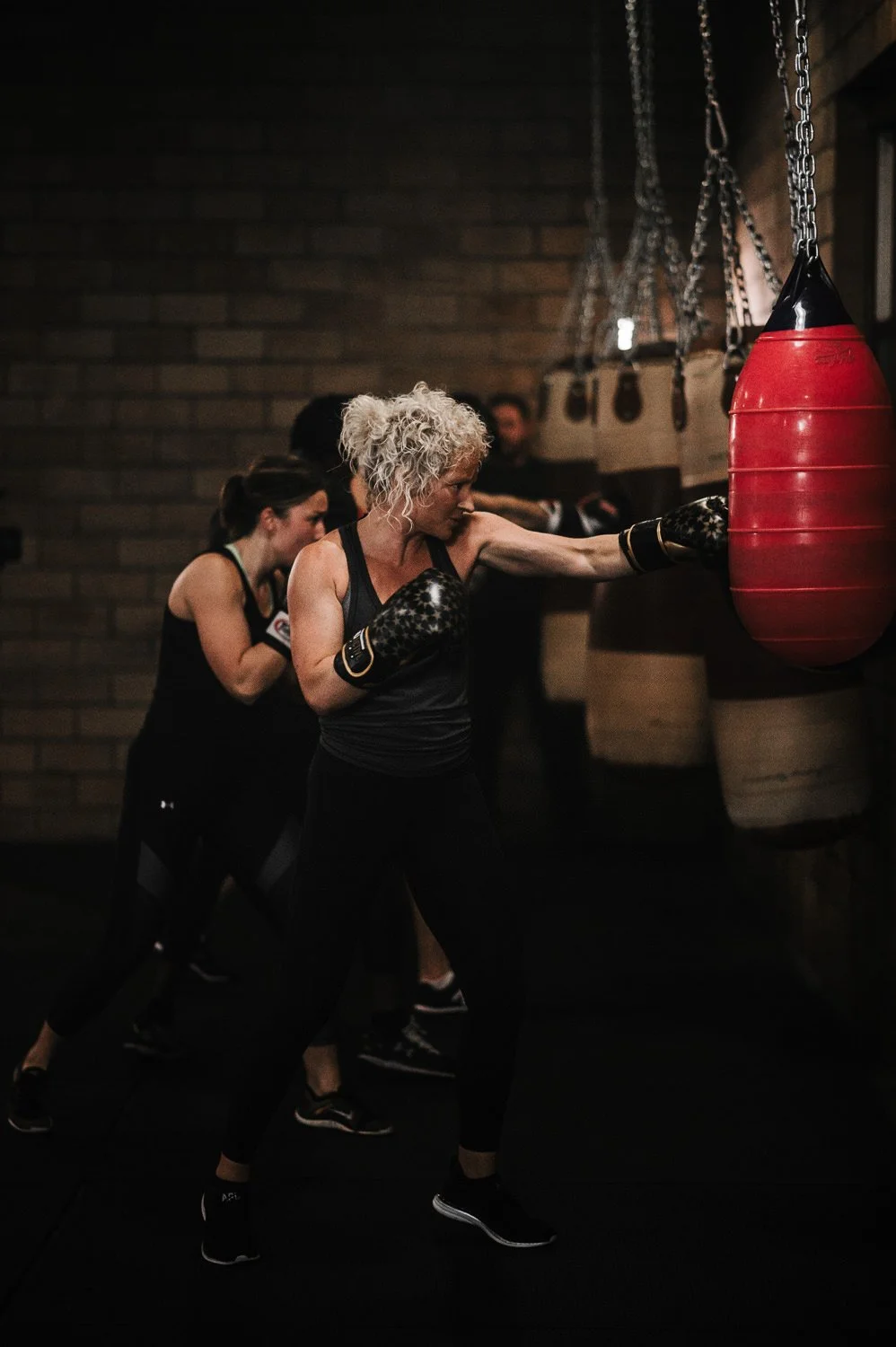 Lifestyle fitness portrait of a woman hitting a punching bag at Beautifully Savage boutique boxing gym in Fort Collins, Colorado
