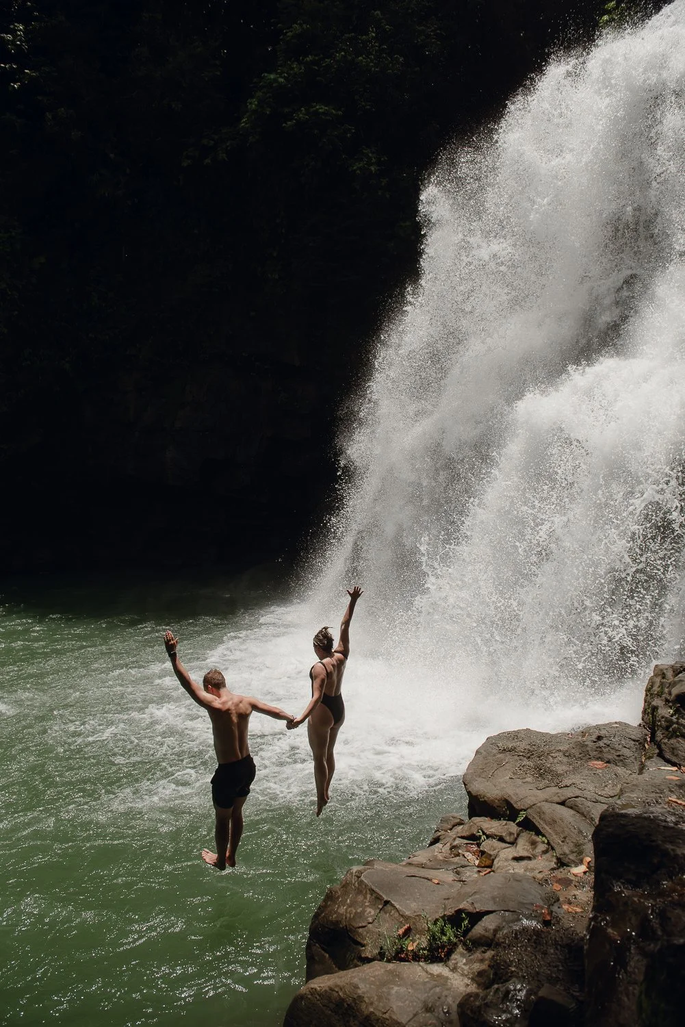 Travel photography of a couple jumping off a cliff at Nuayaca Falls in Uvita, Costa Rica