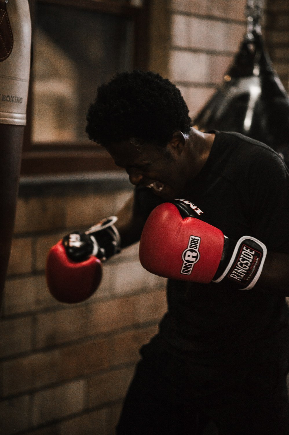 Action fitness photo of a young man hitting a punching bag at Beautifully Savage boutique boxing gym in Fort Collins, Colorado