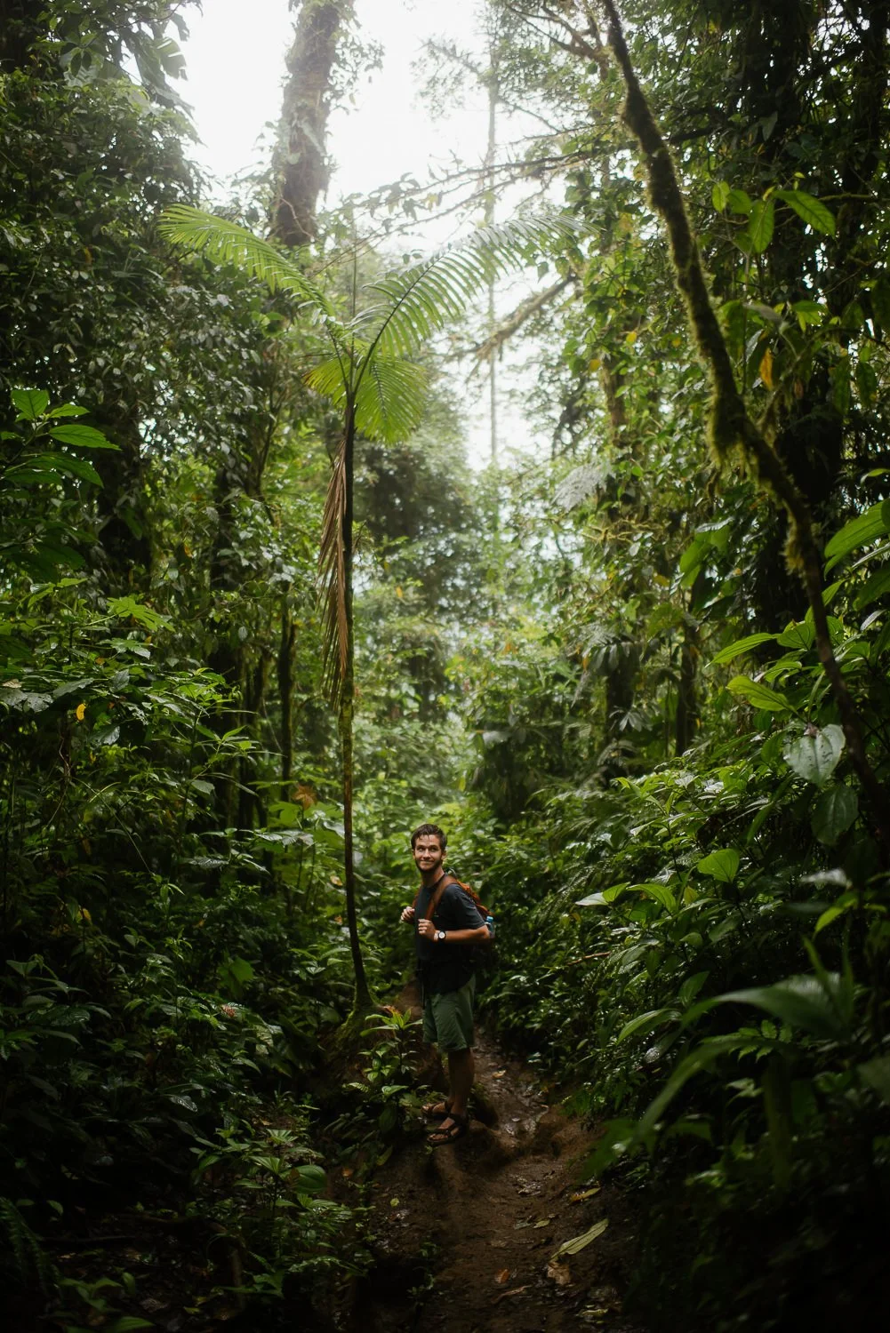 Landscape photograph of a young man hiking through the foggy rainforest on Cerro Chato in Costa Rica