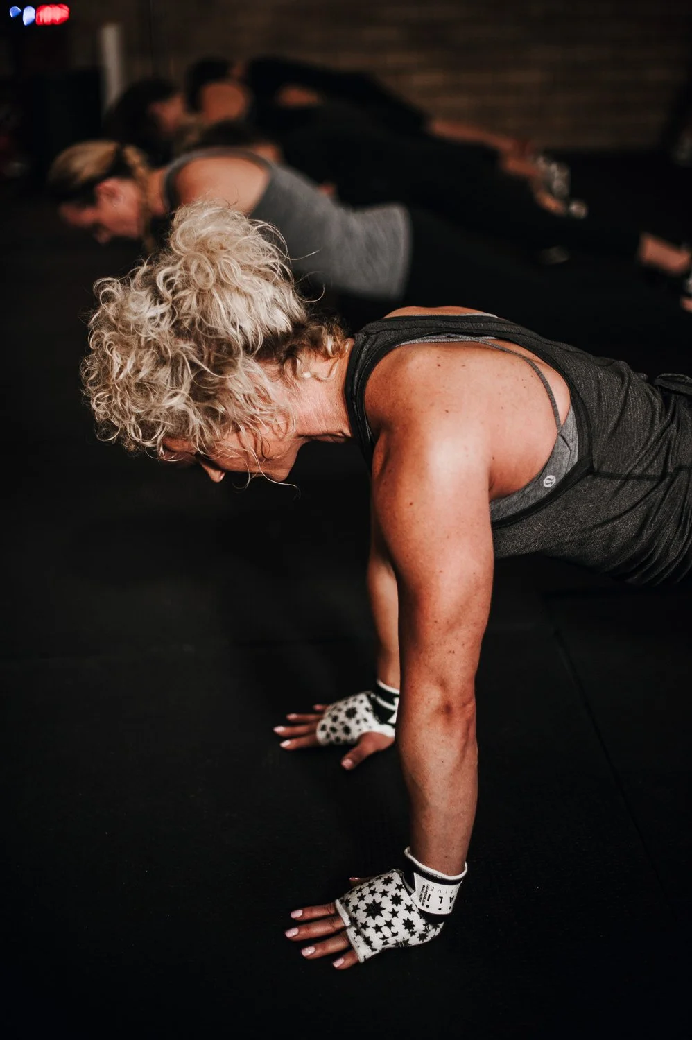 Lifestyle photograph of a woman doing pushups at Beautifully Savage boutique boxing gym in Fort Collins, Colorado