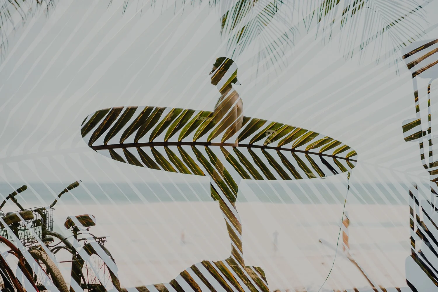 Double exposure image of a surfer holding a surfboard and a palm leaf filling the positive space
