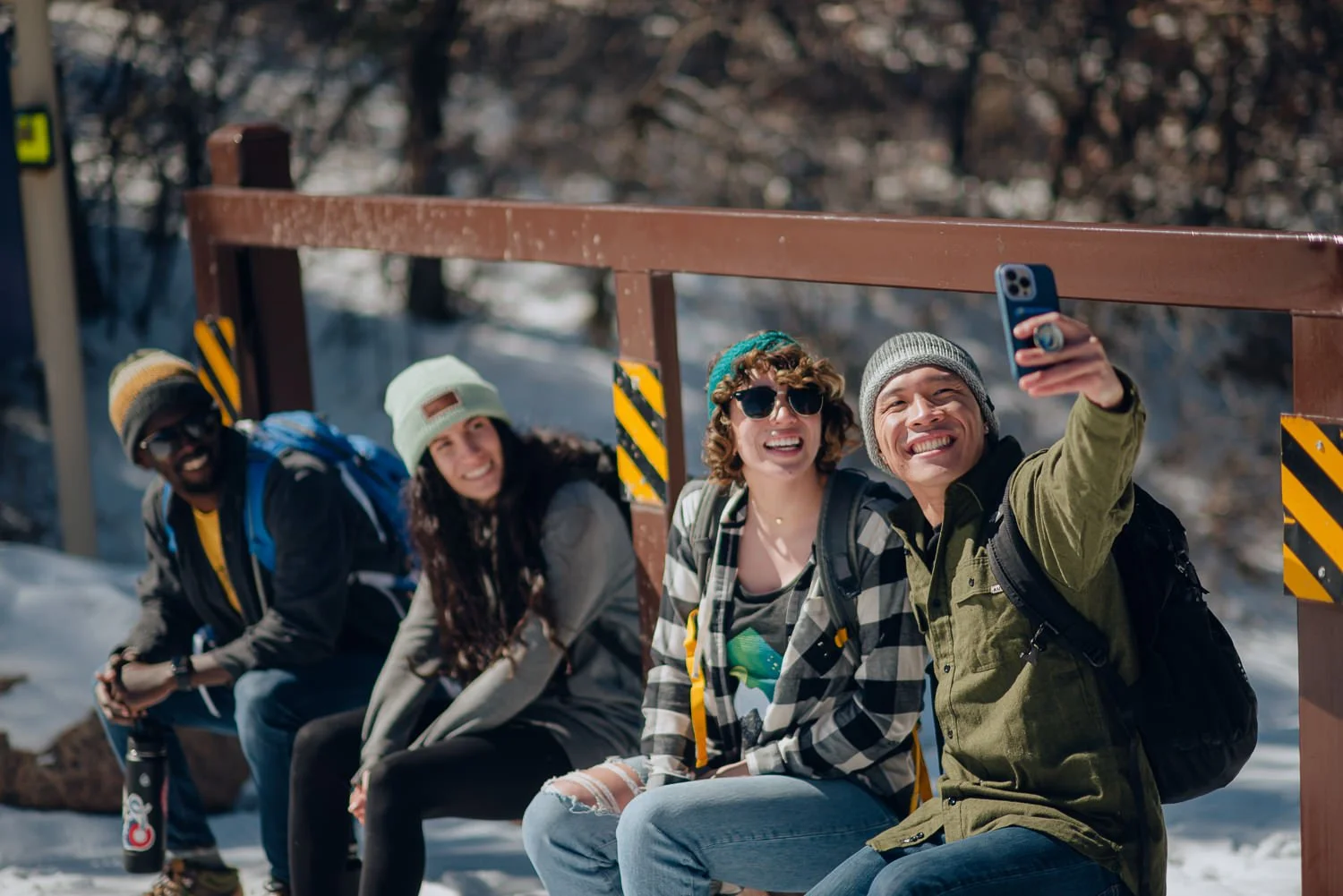 Professional lifestyle photography of a young group of friends taking a selfie on a trail in the snowy mountains in Colorado Springs, Colorado