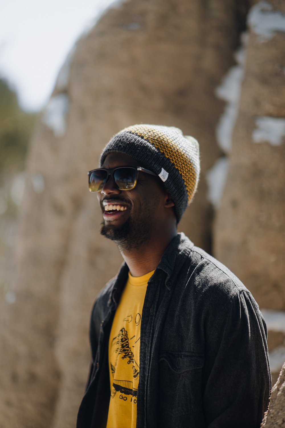 Professional lifestyle photography of young male model wearing Akinz Boardwear beanie and yellow hiking boot tshirt in the snowy mountains in Colorado Springs, Colorado