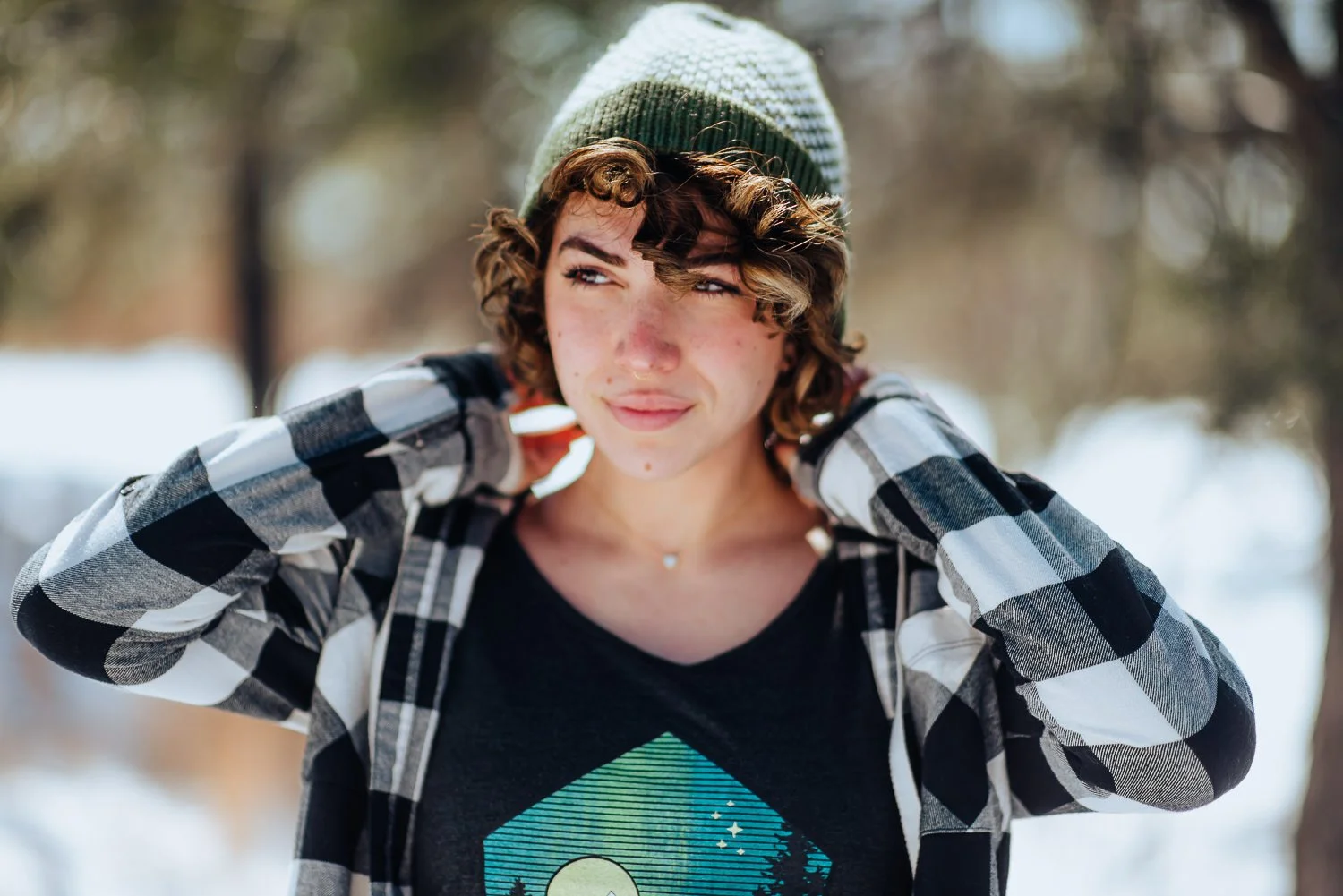 Professional lifestyle photography of young Puerto Rican model with short, curly, brown hair wearing Akinz Boardwear clothing in the snowy mountains in Colorado Springs, Colorado