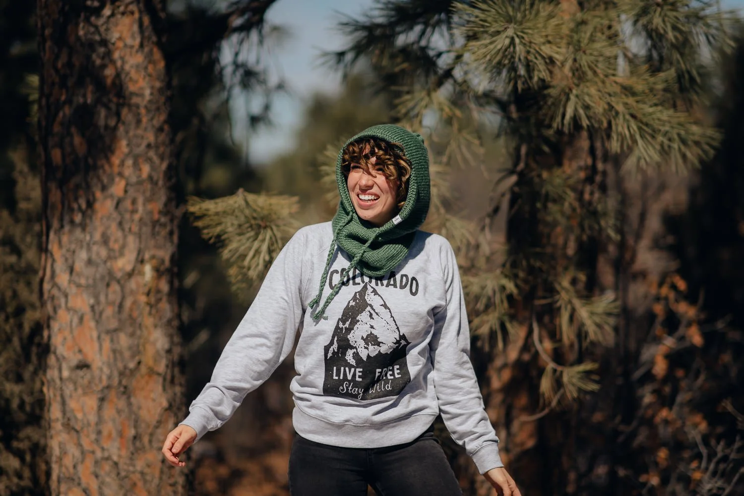 Professional lifestyle photography of young Puerto Rican model with short, curly, brown hair wearing Akinz Boardwear clothing in the snowy mountains in Colorado Springs, Colorado