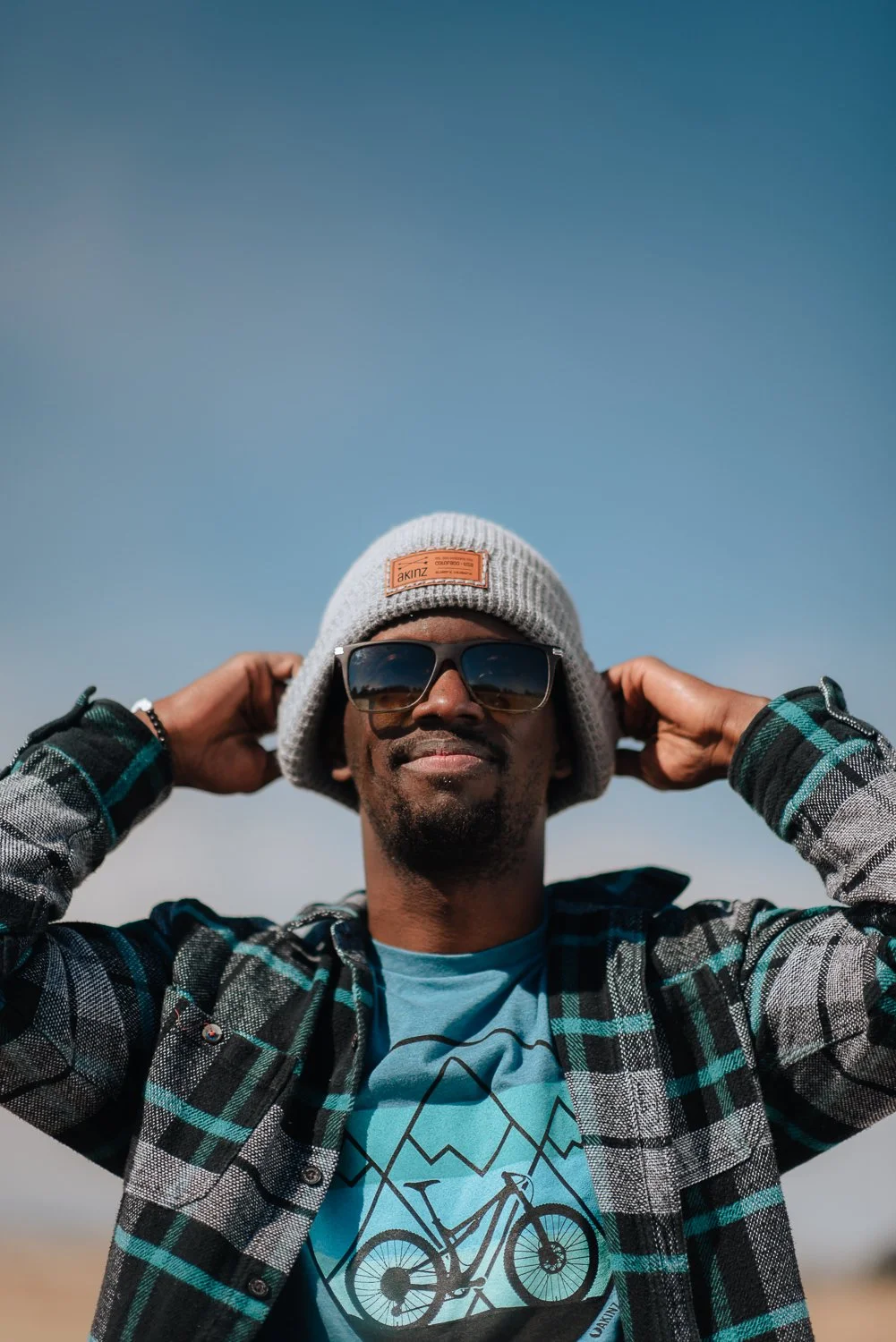 Lifestyle photography of a model wearing an gray beanie and blue bicycle graphic shirt at Palmer Park in Colorado Springs, Colorado for Akinz Boardwear