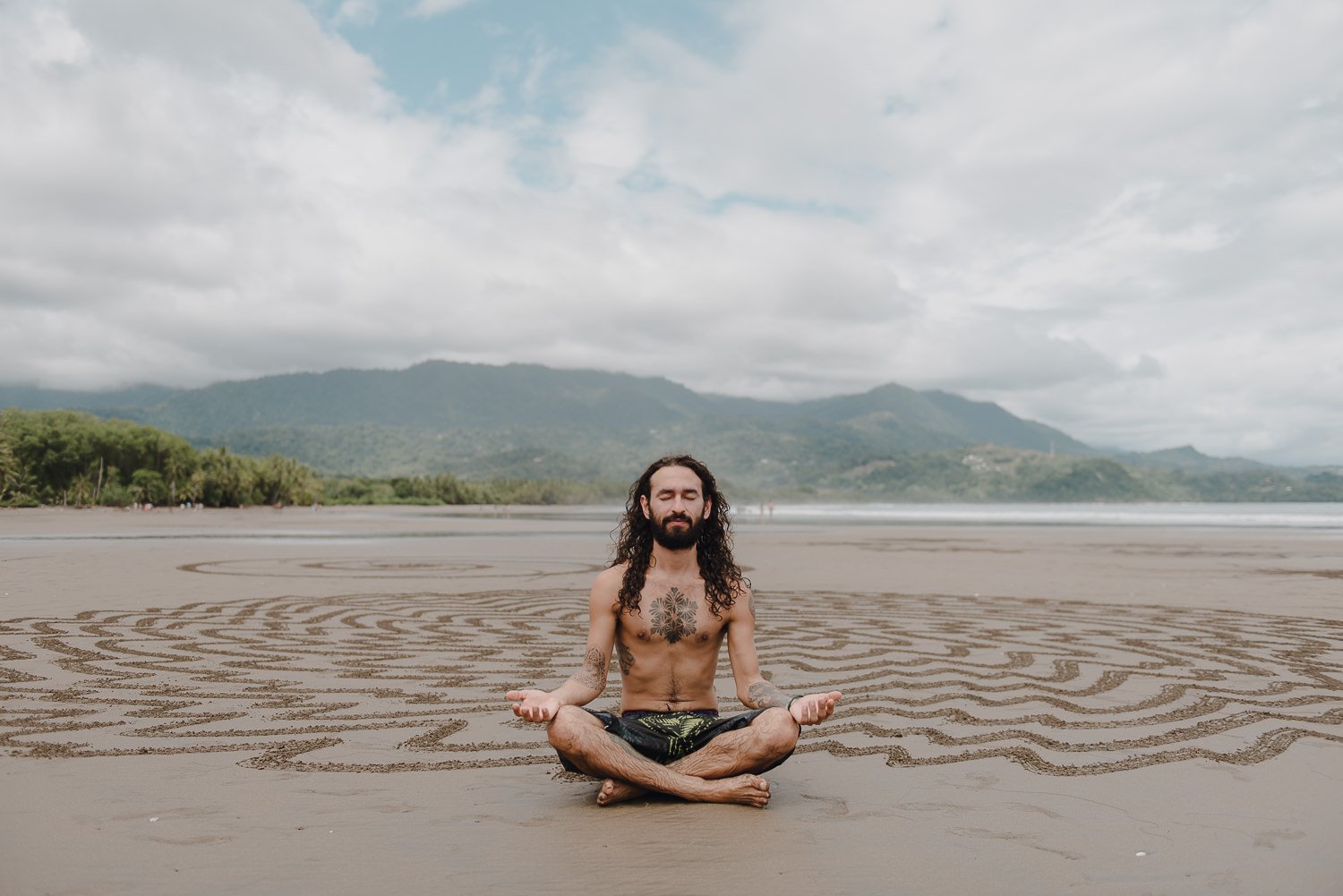 Travel lifestyle portrait of a sand drawing artist at the beach in Uvita, Costa Rica