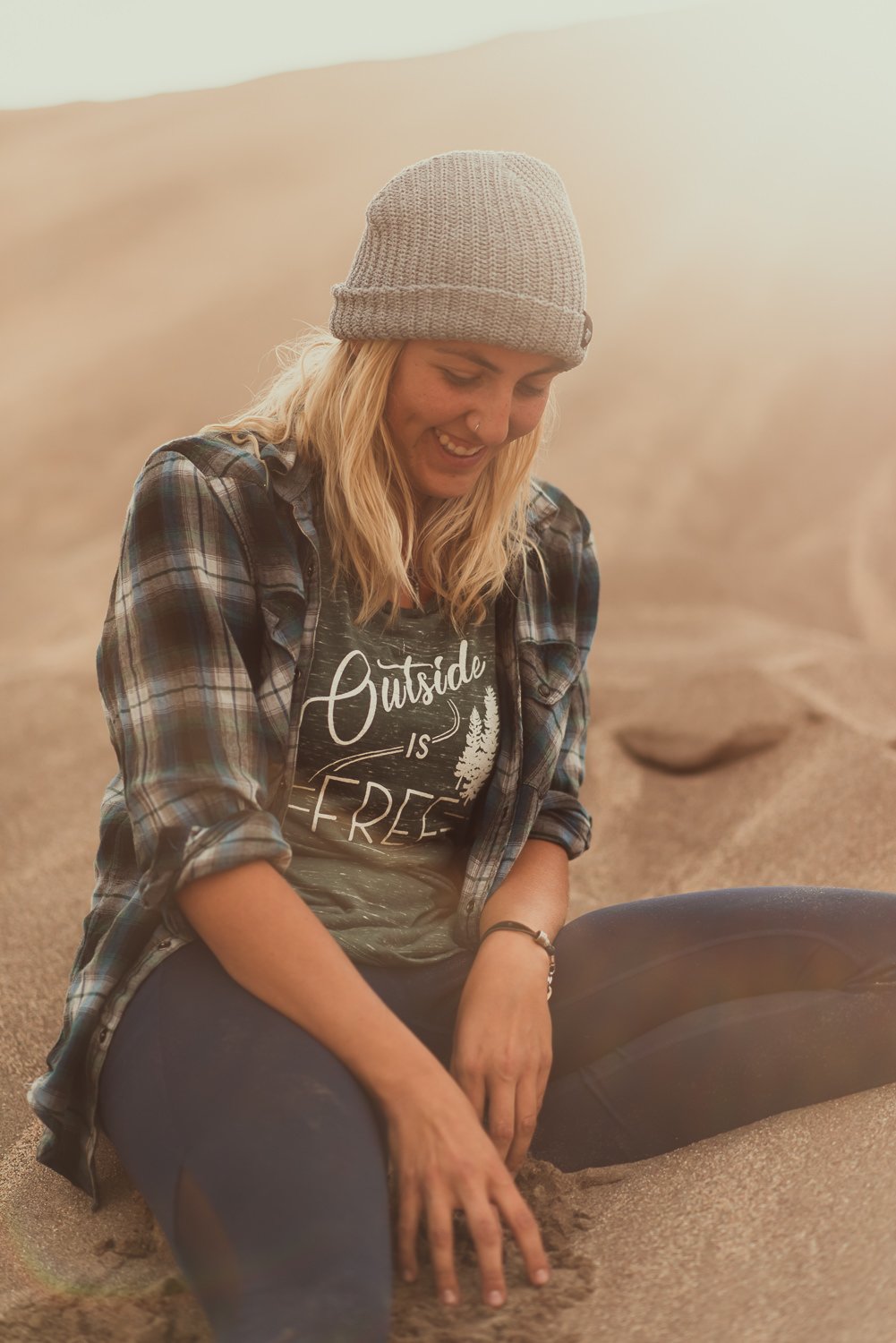 Adventure lifestyle product photography of a blonde girl playing in the sand at Great Sand Dunes National Park in Colorado for Akinz Boardwear