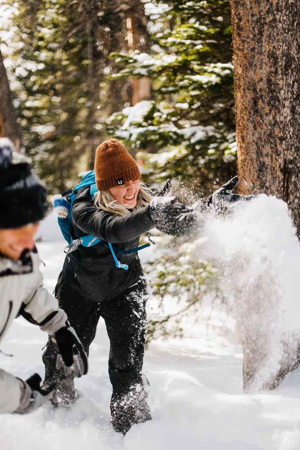 Lifestyle brand photography of blonde girl throwing snow in the woods