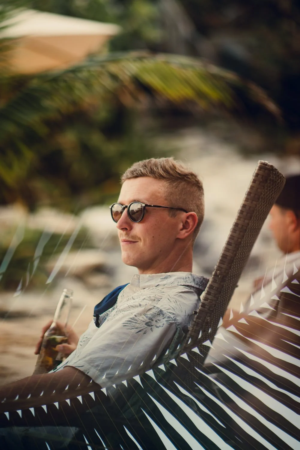 Professional travel lifestyle portrait photography of a man relaxing with a beer in a lounge chair on the beach in Tulum, Mexico 