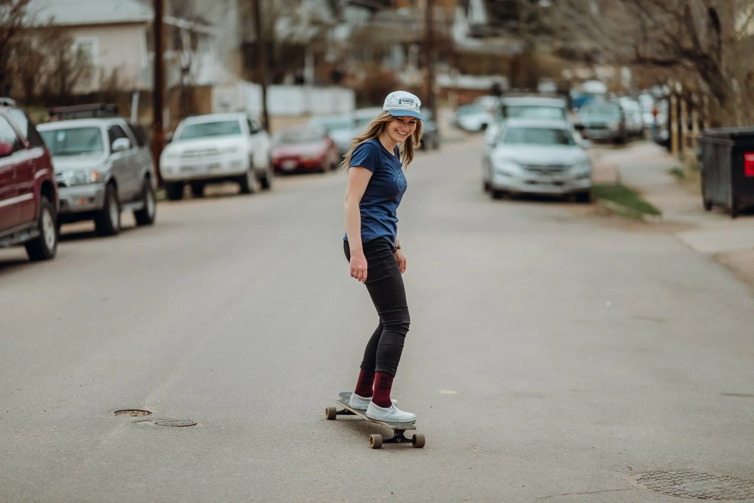 Lifestyle photography of a cute blonde girl riding a longboard in Manitou Springs, Colorado for Akinz Boardwear