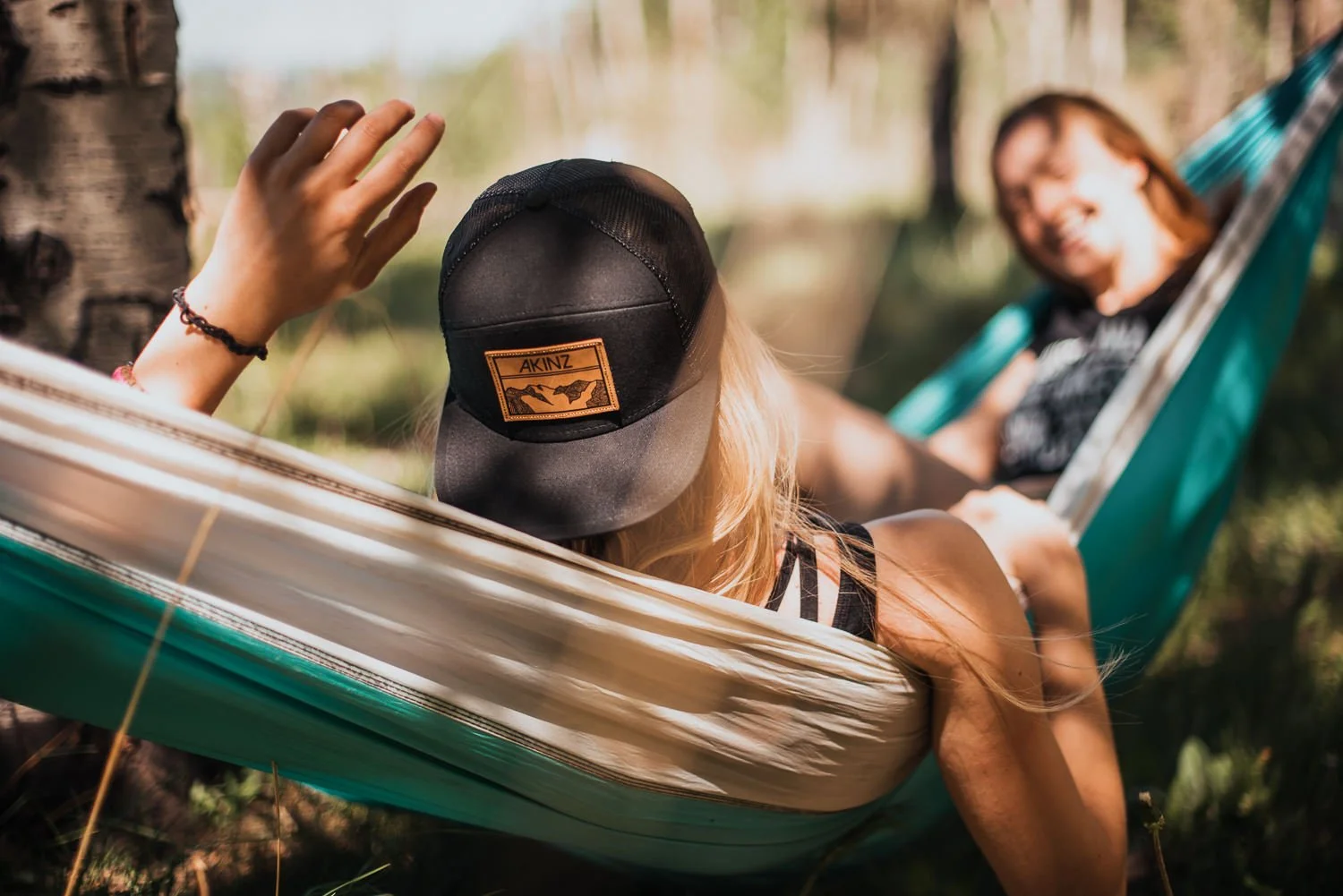 Lifestyle photography of two girls laying in a hammock, wearing Akinz Boardwear gear.