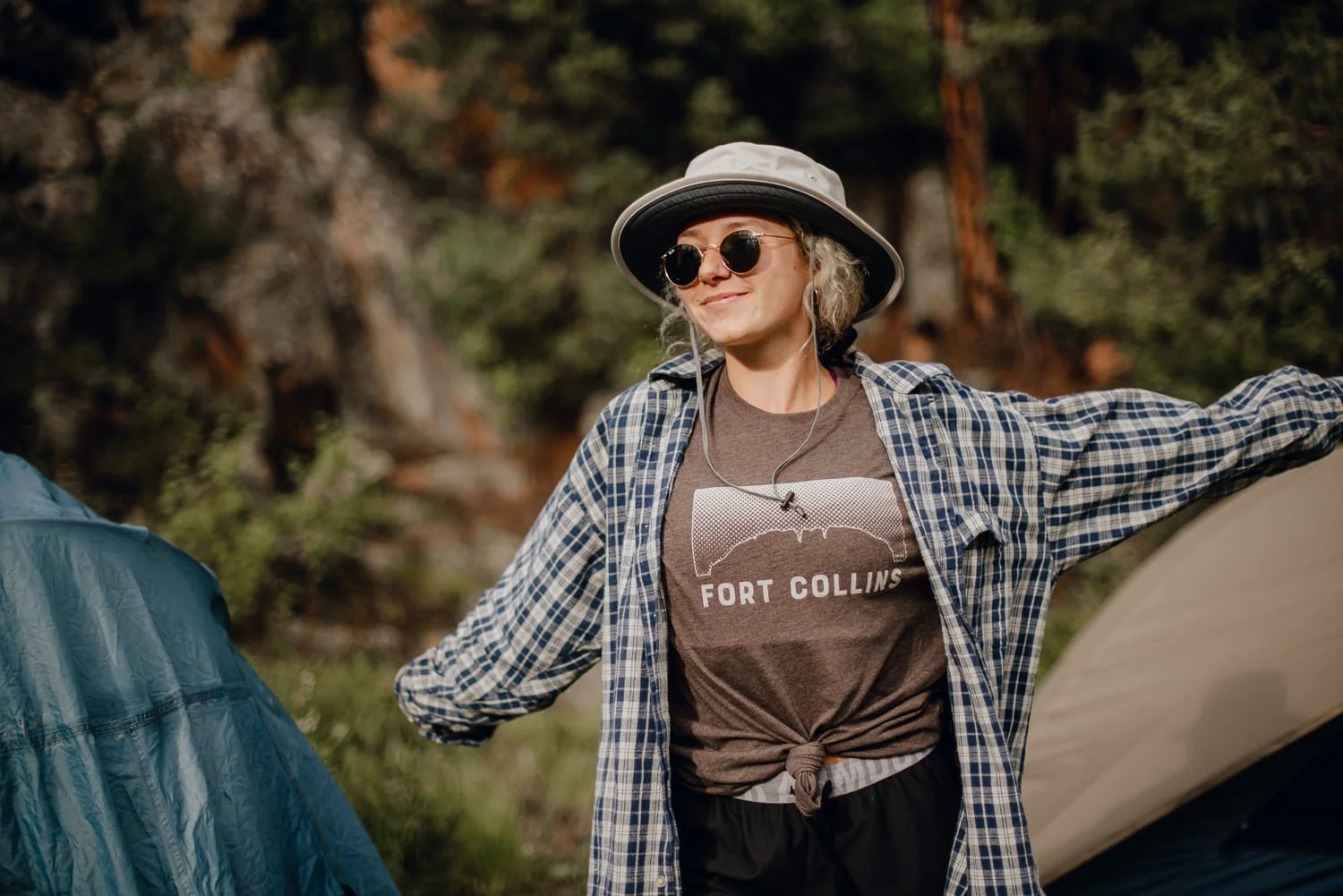 Adventure lifestyle photography of a cute blonde girl in a bucket hat camping in Northern Colorado for Akinz Boardwear