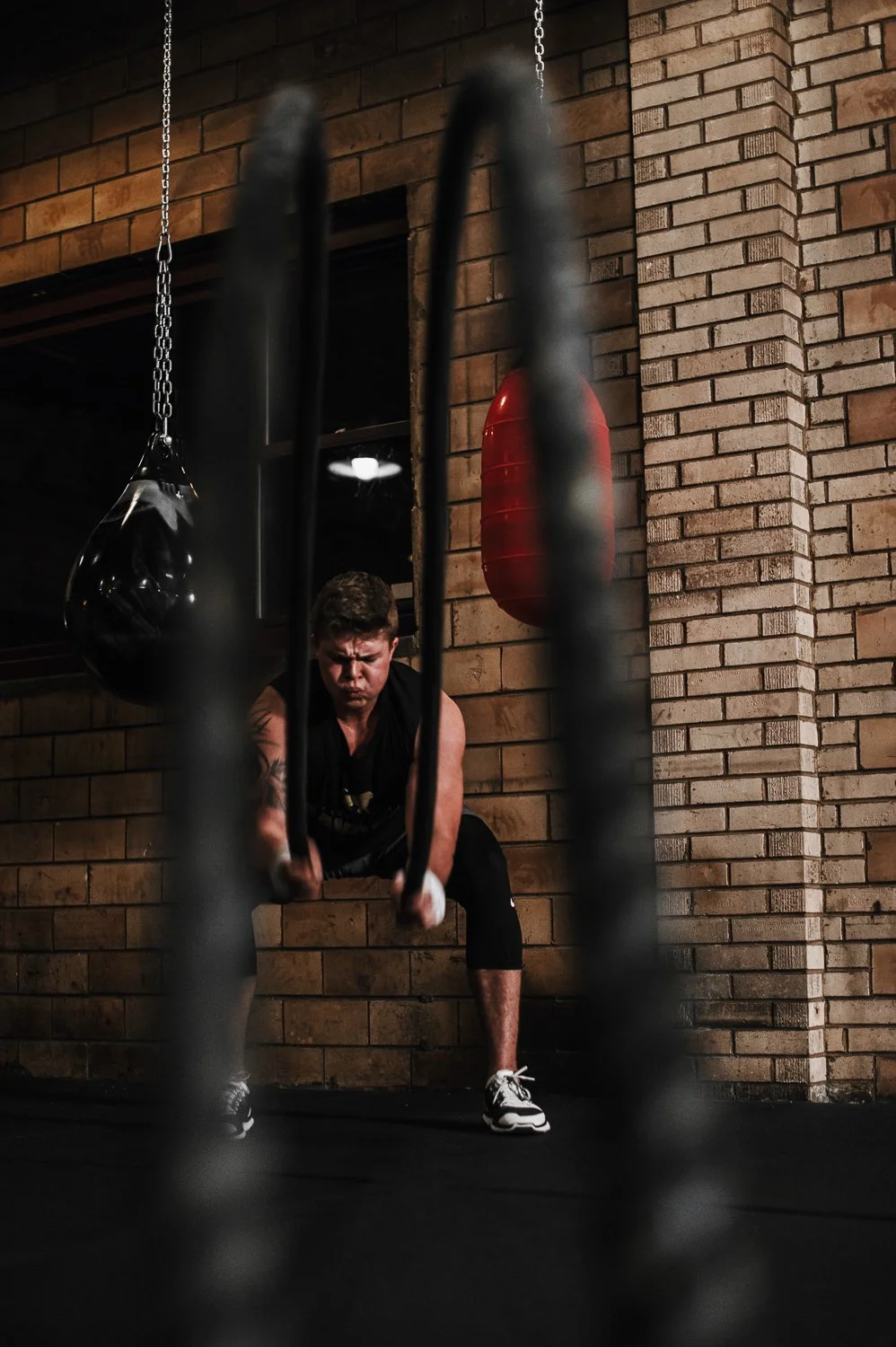 Lifestyle fitness photograph of a man exercising battle ropes at Beautifully Savage boutique boxing gym in Fort Collins, Colorado