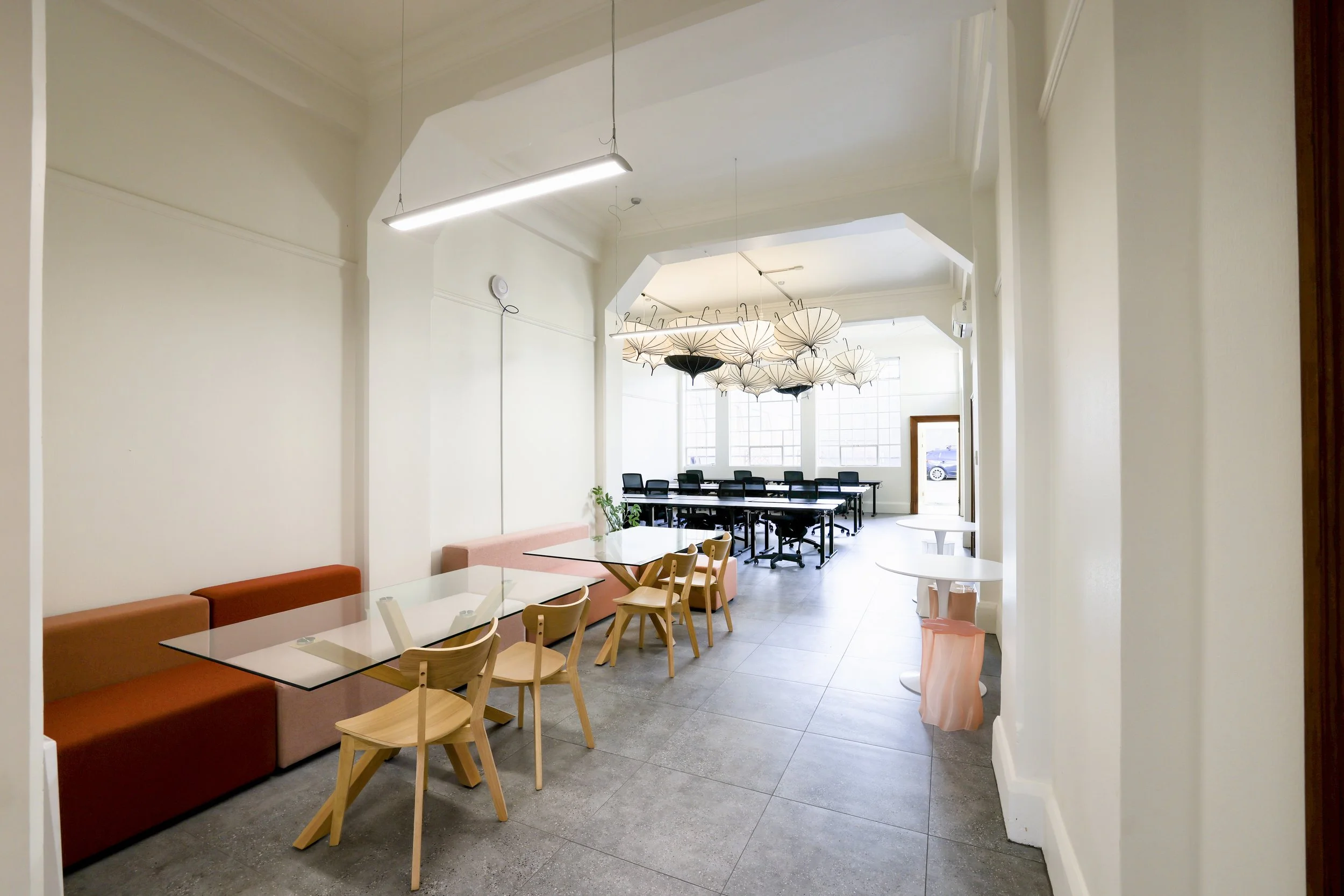 Interior of a bright, modern co-working space with tables, chairs, and artistic hanging umbrellas in Bad Company Hawkes Bay, a co-working space based in Hastings, New Zealand.