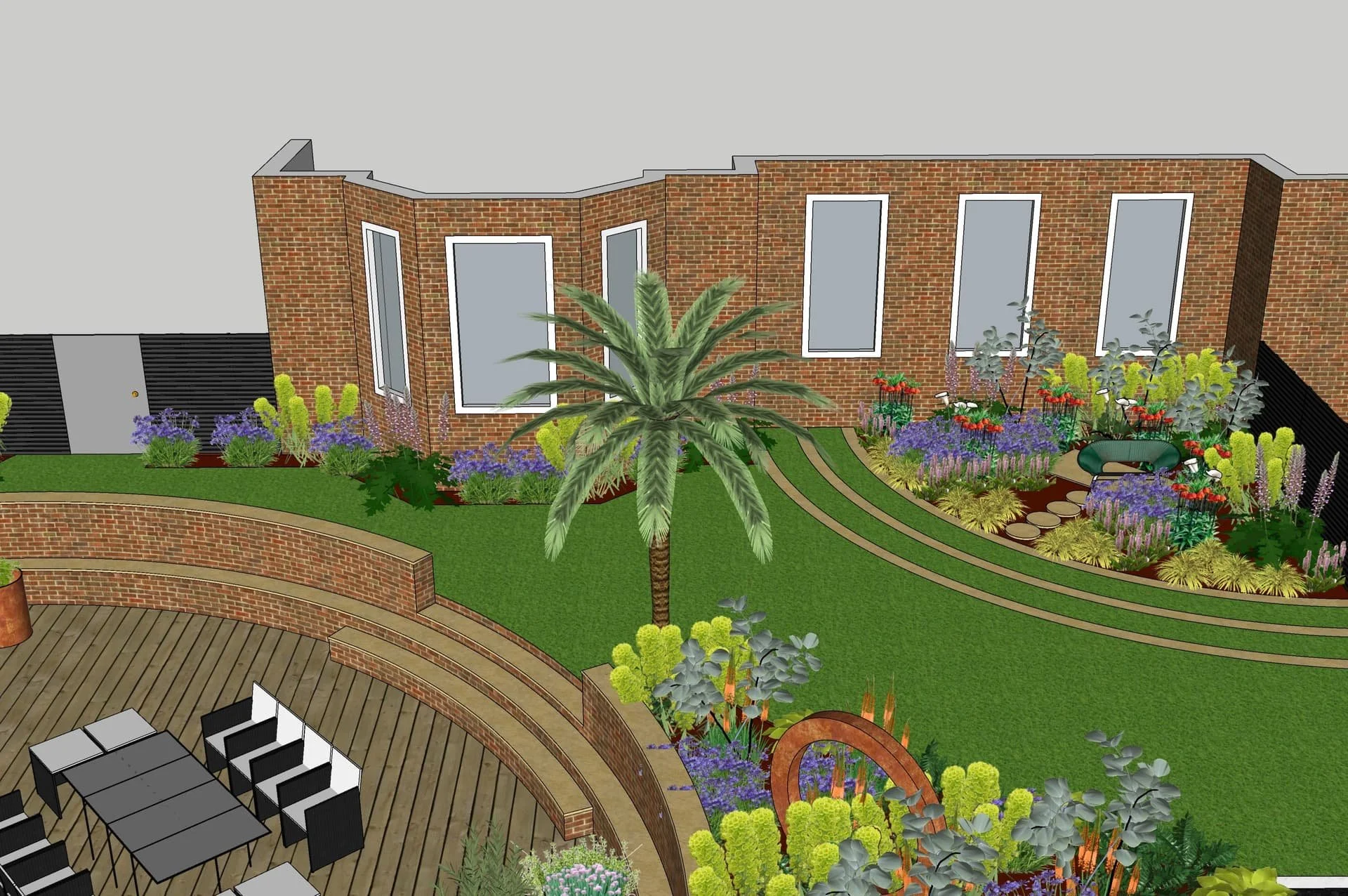 Plan de jardin avec pelouse, palmiers, fleurs colorées, terrasse en bois et maison en briques.