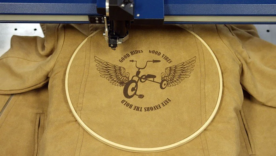Blouson en cuir gravé au laser avec un motif moto ailé et un slogan.