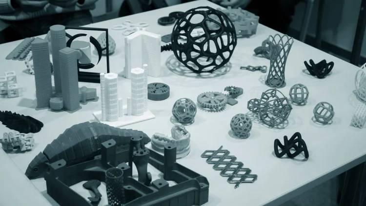 Table couverte de nombreuses pièces et maquettes imprimées en 3D