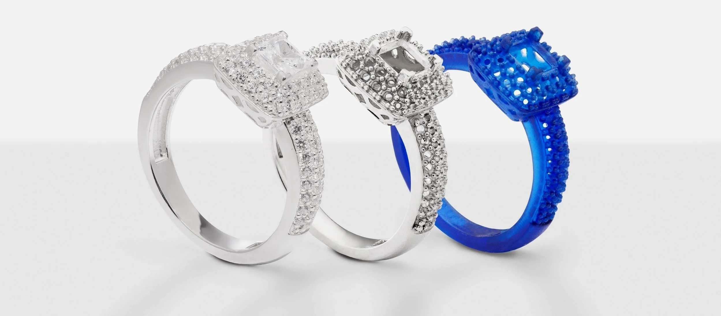 Trois bagues en métal, deux avec des pierres éclatantes, une bleue en plastique.