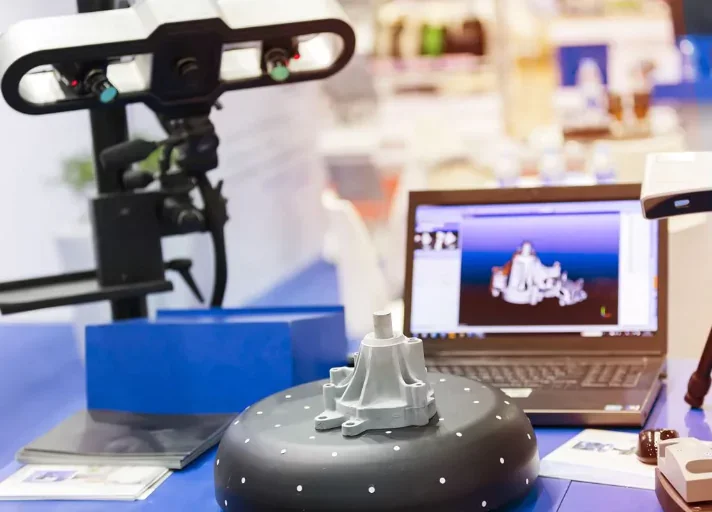 Un robot humanoïde en réparation ou assemblage dans un laboratoire, avec un ordinateur portable affichant une maquette 3D et d'autres équipements technologiques autour.