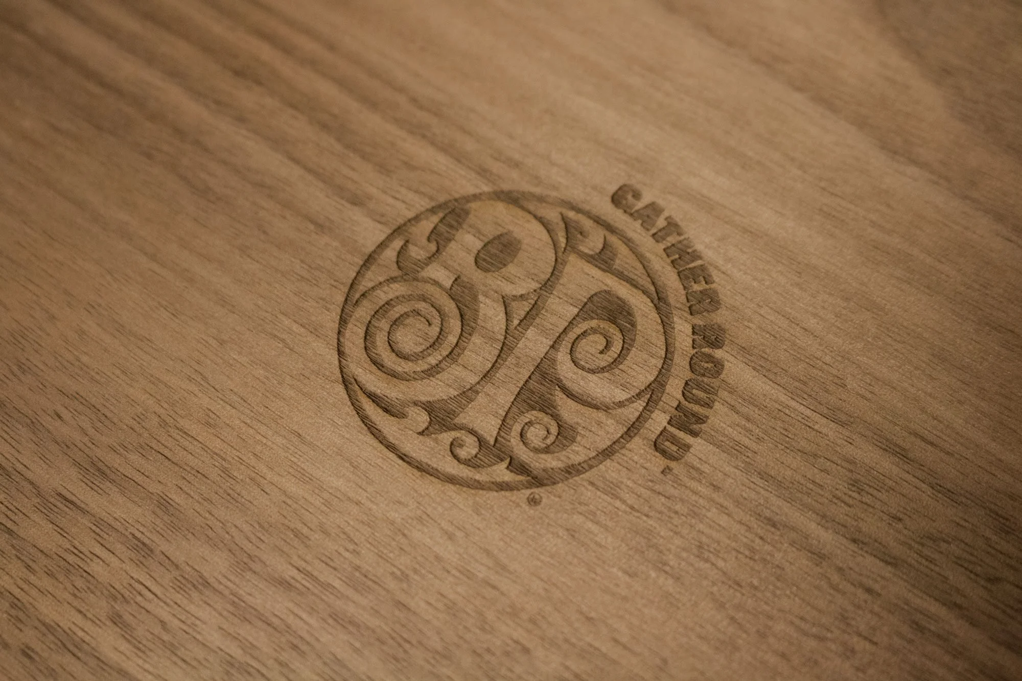 Logo en creux sur une surface en bois avec le texte 'Charred Wood' et un symbole au centre
