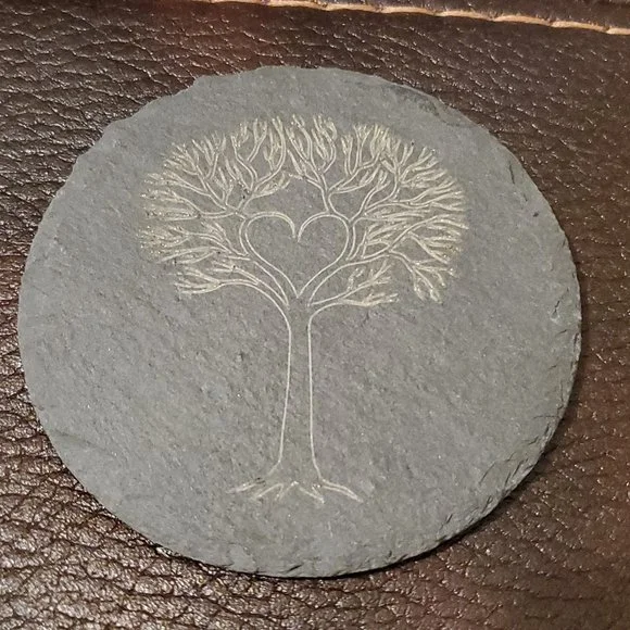 Dessous de verre rond en pierre avec gravure d'un arbre dont les branches forment un cœur.