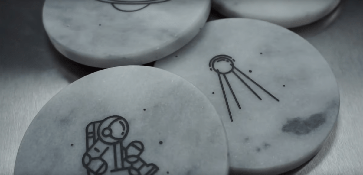 Dessins gravés illustrant un astronaute et un signal radio sur des pierres en marbre.