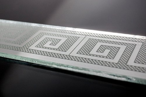 Plaque de verre gravée au laser avec un motif géométrique en spirale.
