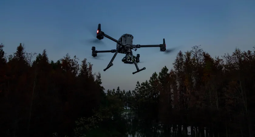 Un drone volant au-dessus d'une forêt pendant le crépuscule.