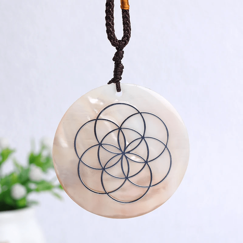 Pendentif rond en nacre gravé au laser d'un motif géométrique de cercles entrelacés.