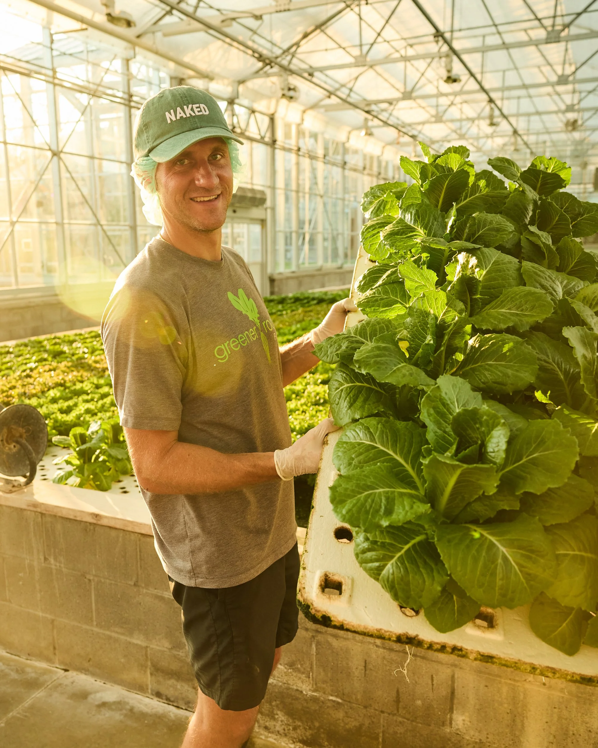 Farmer William from Greener Roots Farm holding up some of the hydroponic greens from his Greenhouse farm.