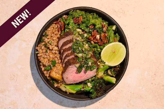 Chimichurri steak & greens plate with sliced grass-fed steak topped with housemade chimichurri, charred broccoli, spiced farro, and pecan kale caesar.