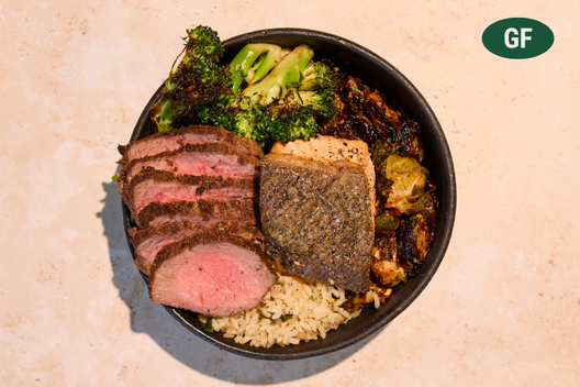 Surf & Turf plate with sliced grass-fed steak, faroe island salmon, chili garlic brussels sprouts, charred broccoli, and brown rice.