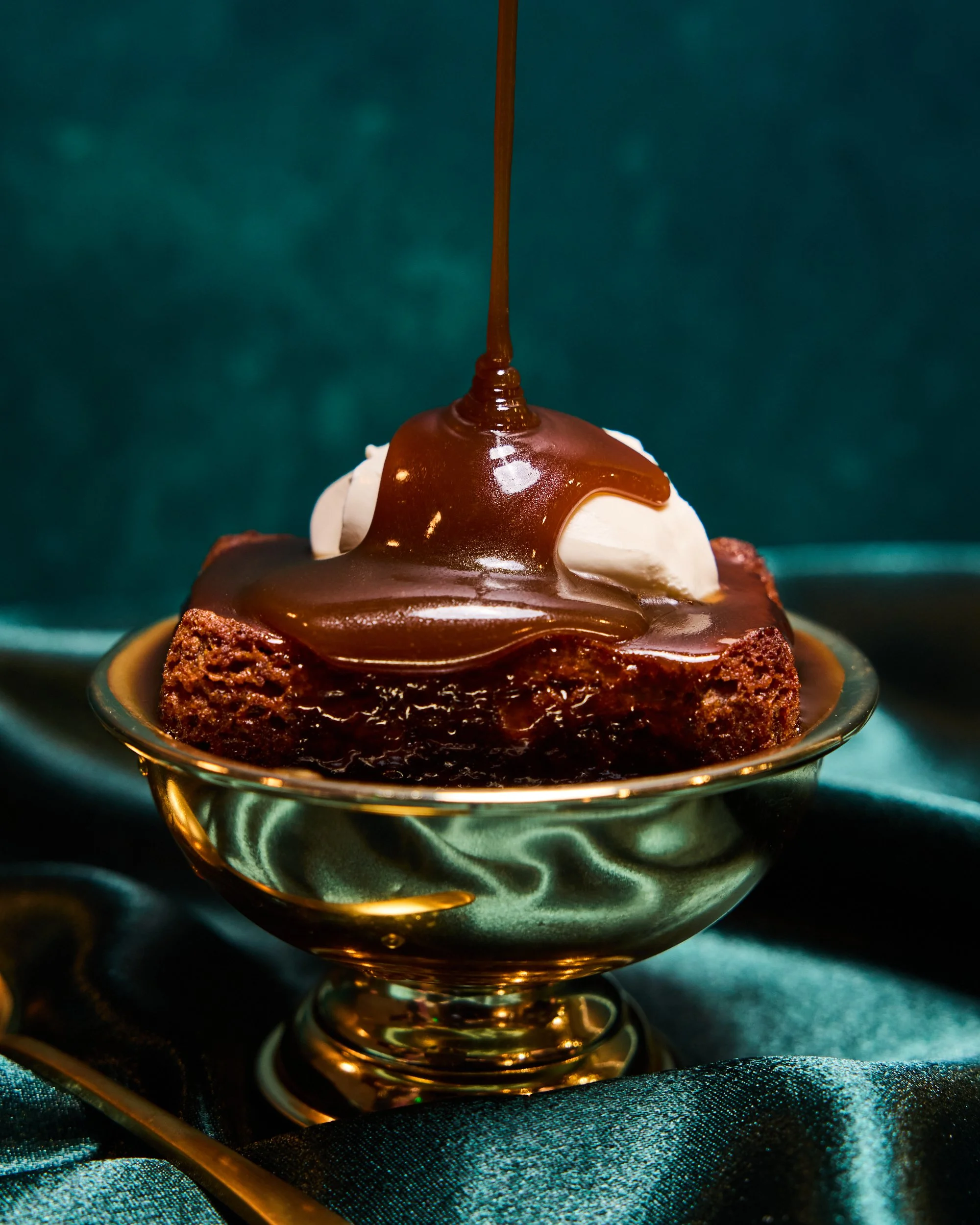 A toffee drizzling on a healthy dessert called sticky toffee date cake. Topped with Crème fraîche